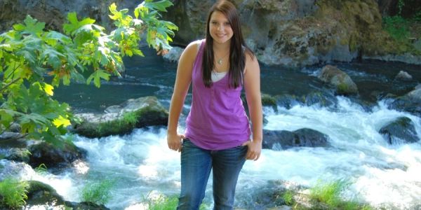 Young woman standing near a flowing river.