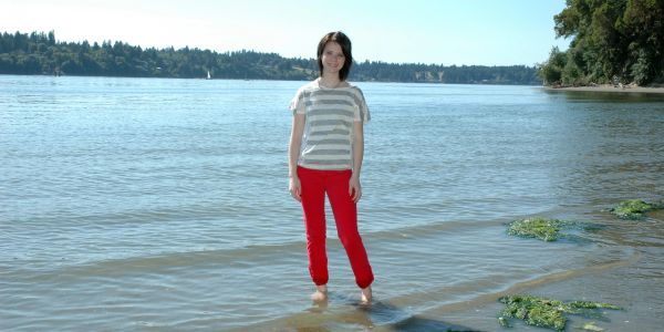 Person standing barefoot in shallow water at lakeside.