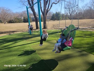 Children enjoying swings on a sunny day at the playground.