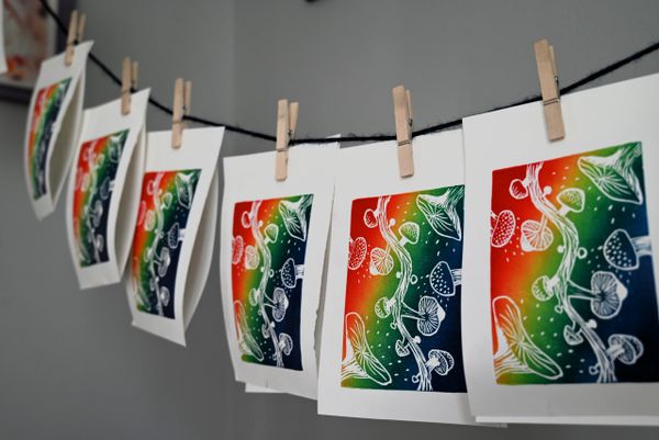 Colorful mushroom prints hanging on a line with clothespins.