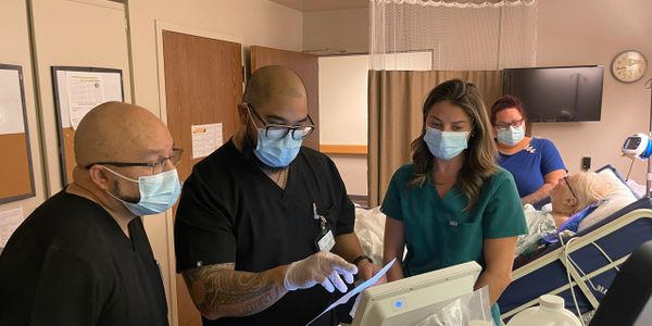 Healthcare professionals reviewing patient data in a hospital room.