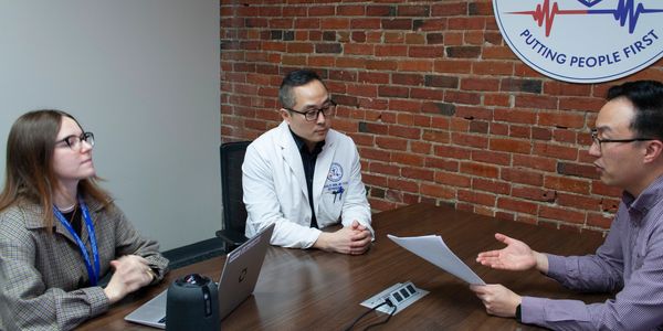 Three professionals engaged in a discussion over documents in an office.