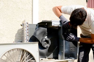 Technician performing professional AC repair service on a residential AC.