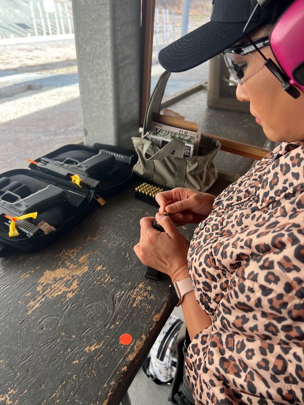 Woman loading Glock magazine at shooting range