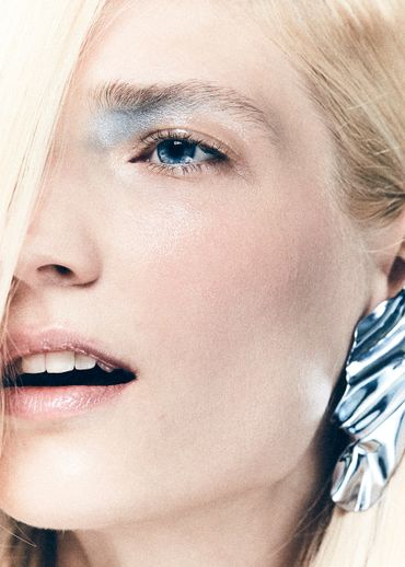 Close-up of a woman with blue eyes, glossy lips, and a large silver earring.