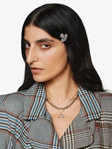 Woman with long dark hair wearing a plaid blazer and pearl hair clip.