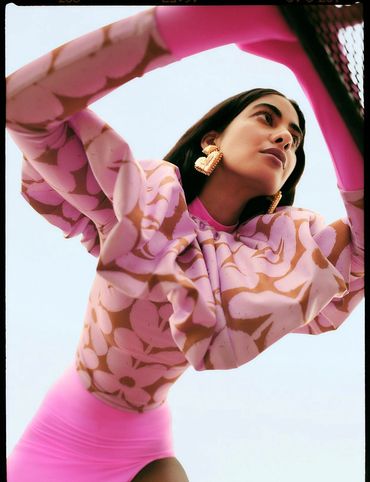 Fashion portrait of a woman in a pink floral outfit with large earrings.