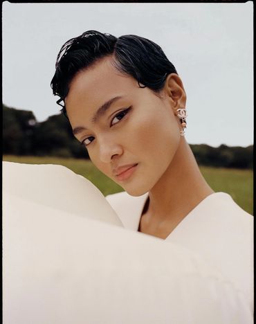 Close-up portrait of a woman with sleek hair and elegant earrings outdoors.