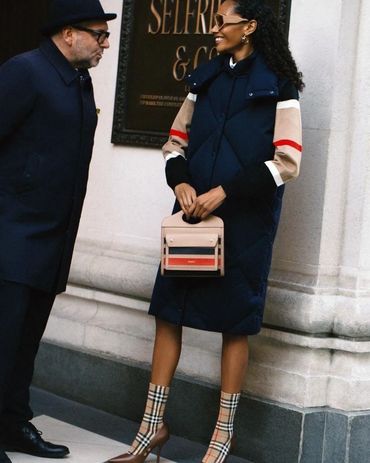 Stylish woman in a navy coat with patterned boots and a chic handbag.
