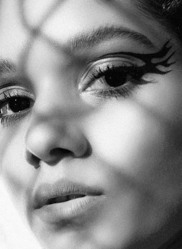 Close-up of a face with artistic winged eyeliner in black and white.