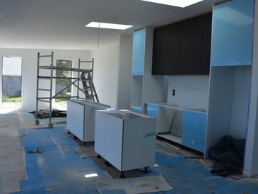 Kitchen under construction with blue protective coverings and scaffolding inside.