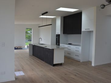 Modern kitchen with black and white cabinetry and wooden flooring.