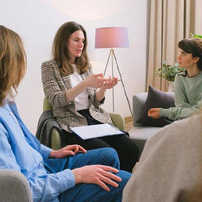 Group therapy session with a woman speaking and others listening attentively.