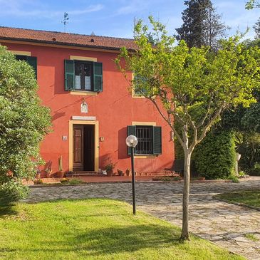 Charming red house with green shutters and a sunny garden.