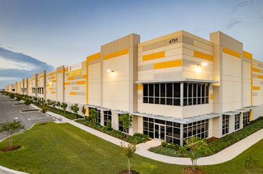 Modern industrial building with yellow accents and large windows at dusk.