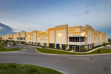 Modern industrial warehouse building with yellow accents under a clear sky.