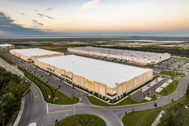 Aerial view of large industrial warehouses at sunset.