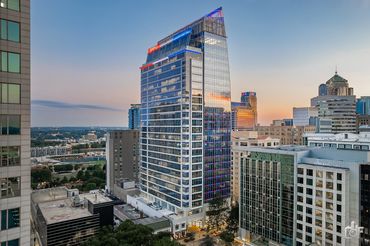 Modern city skyline with a tall glass office building at sunrise.
