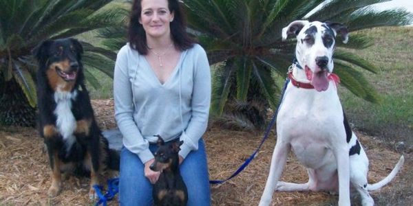 Woman sitting outdoors with three dogs of different breeds.
