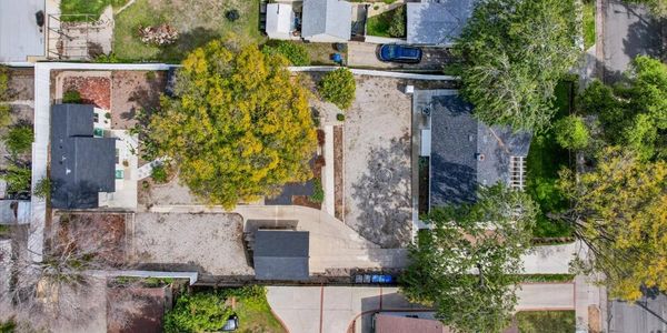 Aerial view of a residential area with houses, trees, and driveways.