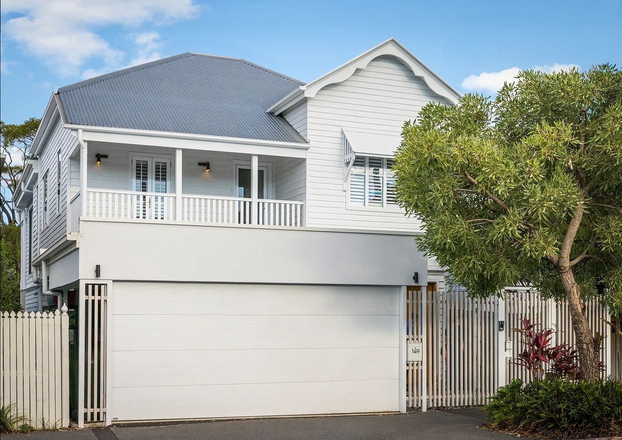 Modern white house with a spacious garage and tree.