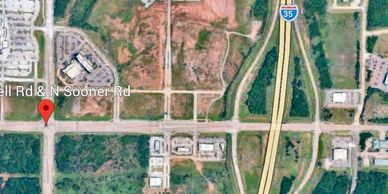 Aerial view of road intersection near I-35 highway with surrounding vacant land and buildings.