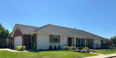 Single-story suburban house with a well-maintained lawn under clear blue sky.