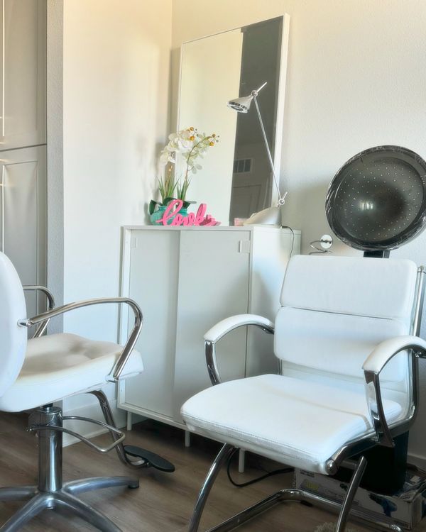 Bright beauty salon corner with white chairs and a cabinet.