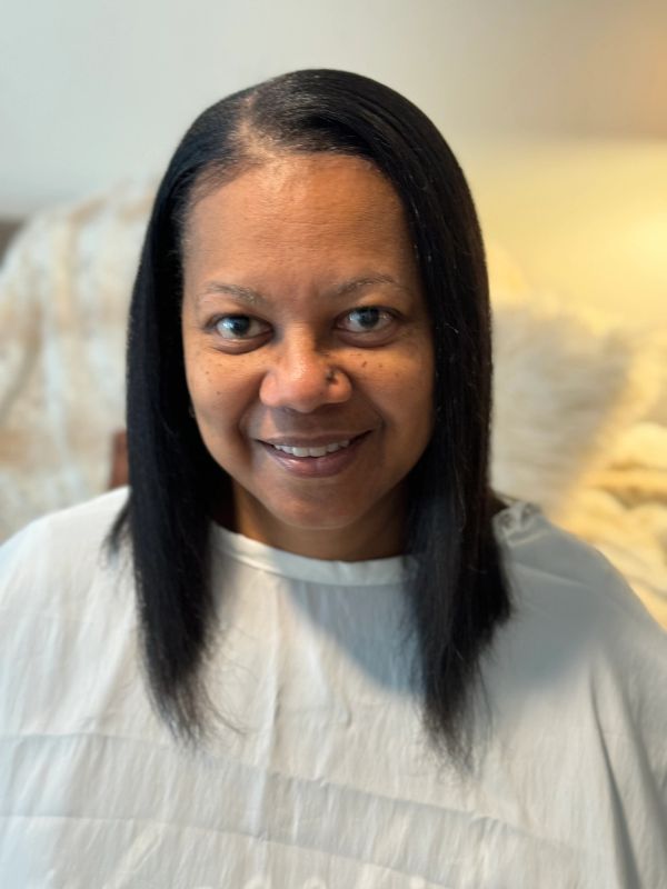 Smiling woman with straight black hair and white top.