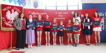 Group of children and adults holding certificates at a school event.
