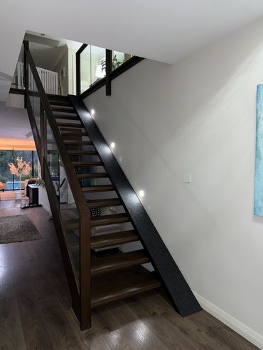 Modern wooden staircase with glass railing.