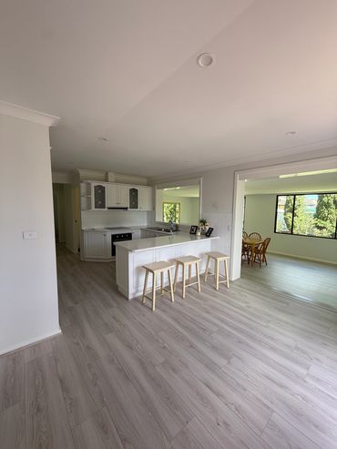 Bright modern kitchen with stools and dining area.