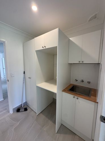 Laundry area with white cabinetry and sink.