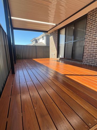 Modern covered wooden deck with sliding glass doors.