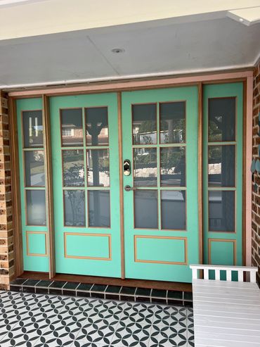 Double turquoise front doors with glass panels and a patterned tiled floor.