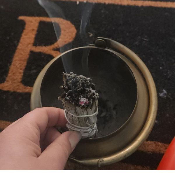 Hand holding a burning sage bundle.