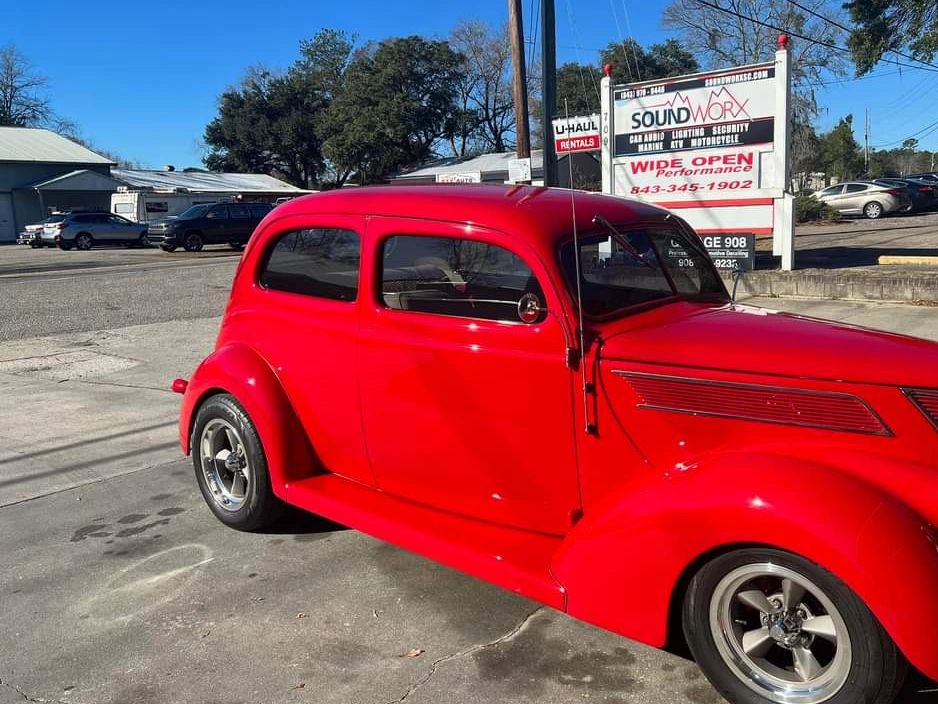 Red classic car parked by the SoundWorx car audio shop sign on Miles Jamison Road in Summerville, SC