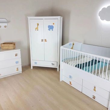 White nursery furniture set with animal stickers in a clean room.
