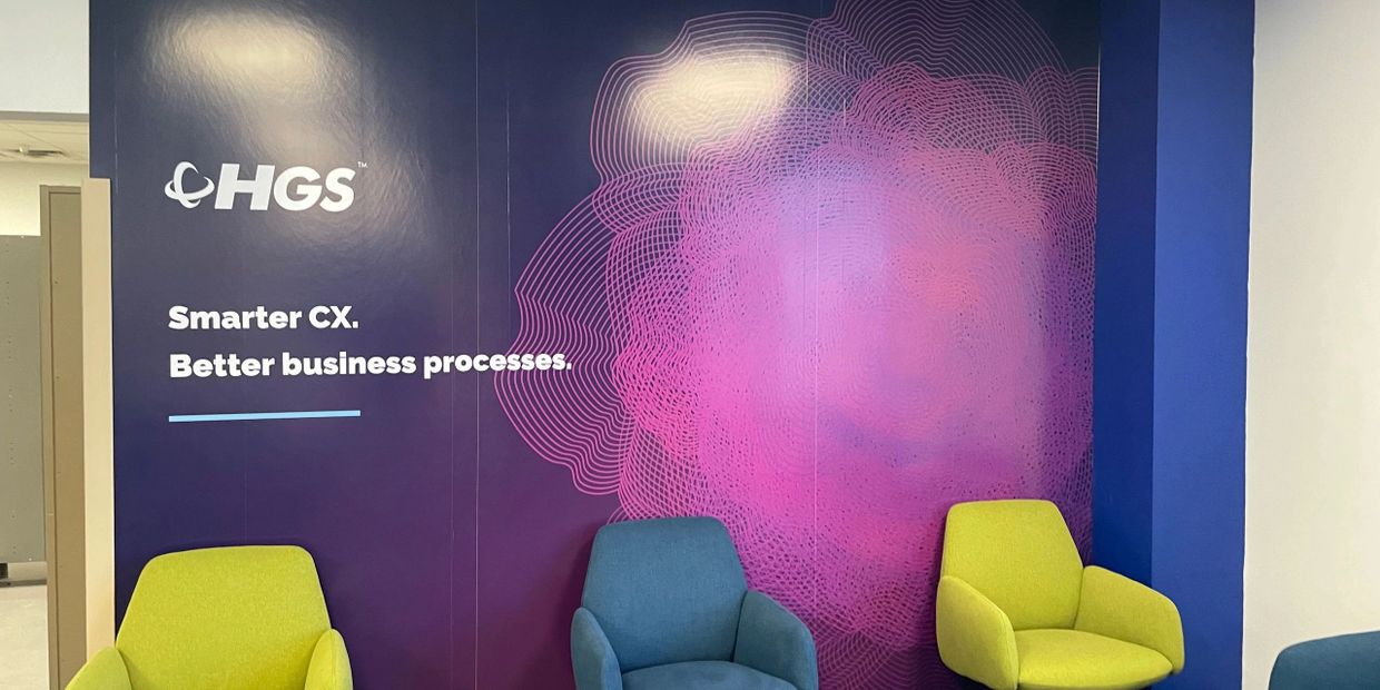 Modern office corner with colorful chairs and a vibrant company wall design.