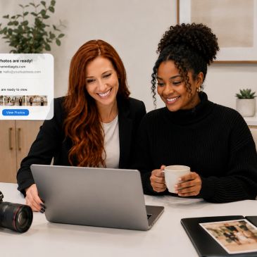 Two women smiling while looking at a laptop.