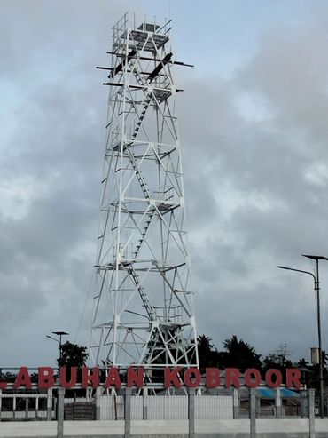 Tall white metal tower with a zigzag staircase and 'LABUHAN KUBROOR' sign below.
