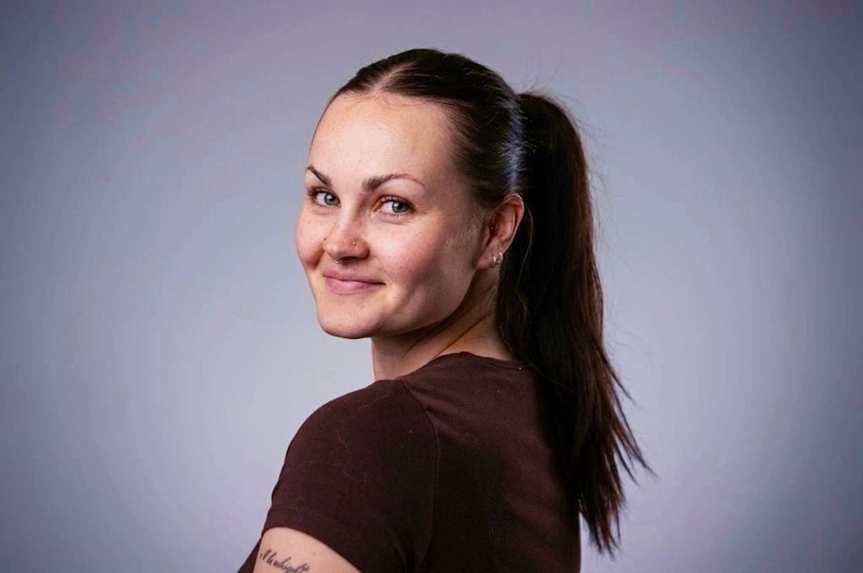 Young woman with a ponytail smiling over her shoulder.