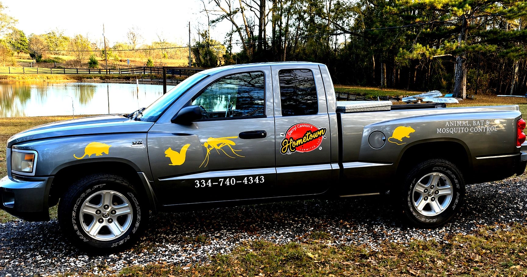 Gray truck with pest control advertising and animal icons.