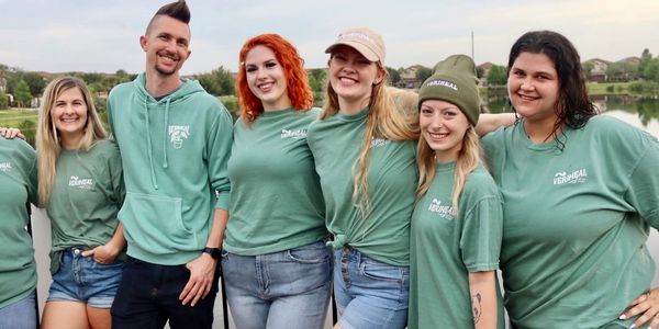 A group of cannabis influencers wearing teal Veriheal shirts on a dock