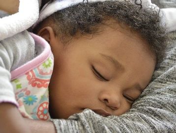 infant sleeping peacefully on caregiver