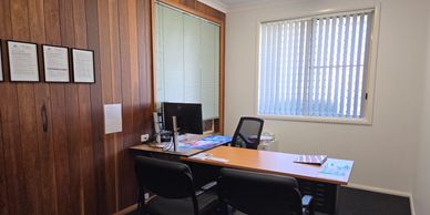 A small office with wooden walls and a desk.