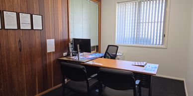 A small office with wooden walls and a desk.
