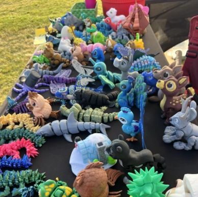 Colorful clay animal sculptures displayed on a table outdoors.
