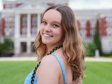 Smiling young woman outdoors with blurred building background.