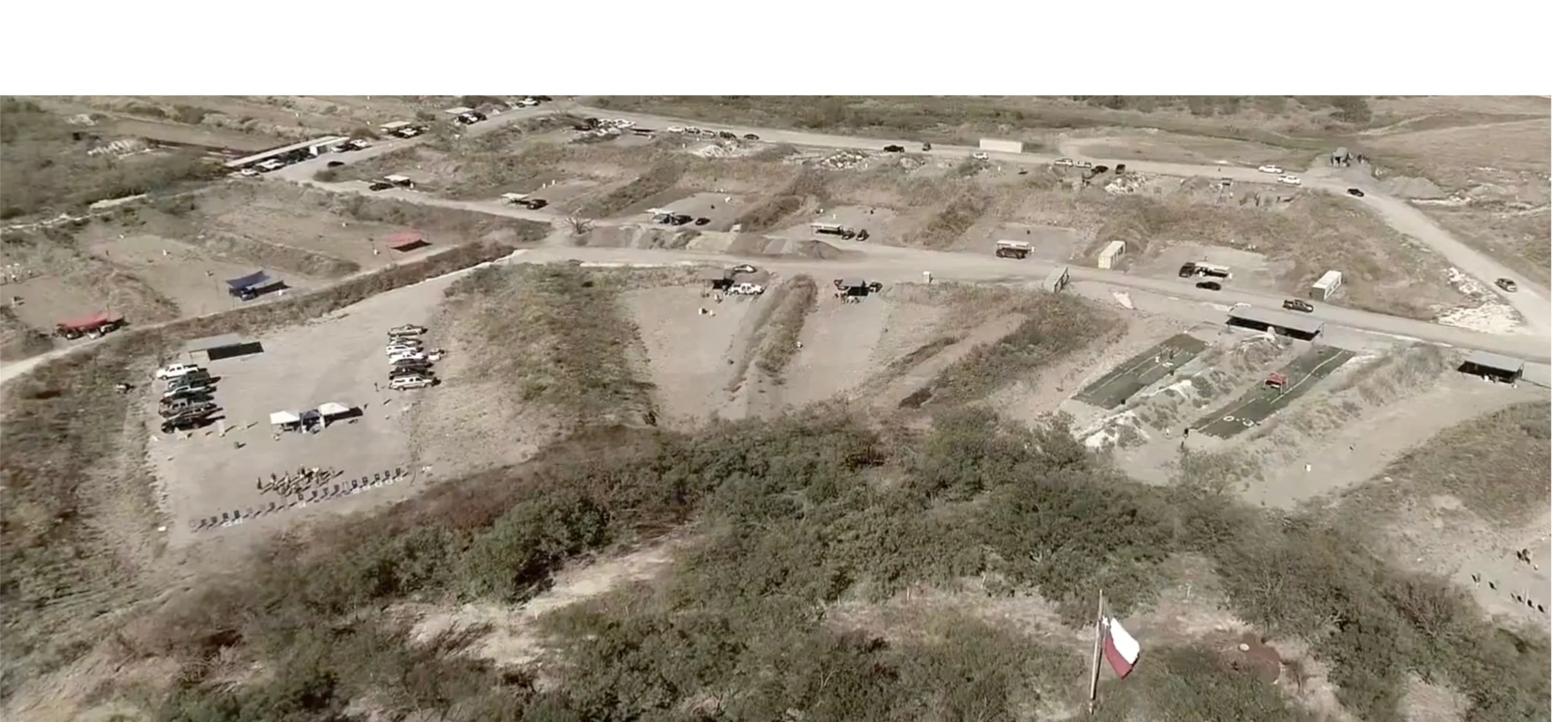 A shooting range, ETTS hosting a community safety fundraiser, with multiple lanes and vehicles parked nearby under a clear sky.